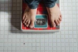 weighing an elderly patient on a medical standing scale in a clinical setting